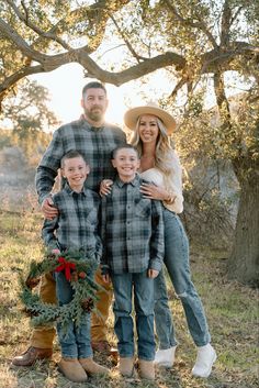 a man and two children standing in front of a tree with a wreath on it