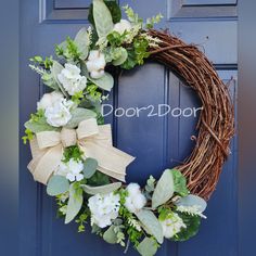 a wreath with white flowers and greenery hangs on a blue door