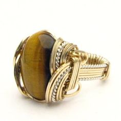 "Handmade Wire Wrap Two Tone Sterling Silver/14kt Gold Filled Tiger Eye Agate Ring  Sizing and shipping is ALWAYS FREE with a 14 day \"No Questions Asked\" return policy. Gemstone sizes available: XS (16x12mm 5/8x1/2 inch) S (18x13mm 3/4x1/2 inch 10+ct) M (25x18mm 1x3/4 inch 20+ct) L (30x22mm 11/8 x7/8 inch 25+ct) This ring is made with real gems. I made it myself, so if you see a setting you like and want a different gem in it, I can put in another one as they are not finished. I can probably do it for the same price or real close. I can make these either in gold or sterling silver; just email me for a price. If any of the wires look loose in the picture it is because I do not finish them until I size them. They will not be loose when you get them.  We can also offer matching earrings, pe Artisan Oval Hand-wrapped Jewelry, Artisan Hand Wrapped Oval Jewelry, Brown Polished Agate Jewelry, Gold Cabochon Agate Jewelry, Gold Agate Jewelry With Polished Finish, Gold Agate Cabochon Rings, Handmade Oval Gold Gemstones, Gold Agate Cabochon Jewelry, Yellow Gold Agate Ring