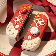 two nintendo wii game controllers sitting on top of a plate next to a red ribbon