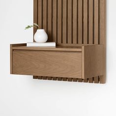 a white vase sitting on top of a wooden shelf