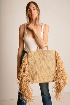 Raffina tote with woven handles, and 12" draped fringe at sides. Tote measures 14.5" wide (without fringe), 16" tall and 4" in depth. Handcrafted in France. Bohemian Straw Bag With Tassels For Shopping, Rectangular Fringe Bags For Shopping, Everyday Use Straw Tote Bag With Fringe, Fringe Straw Tote Bag For Travel, Shopping Tote Straw Bag With Fringe, Bohemian Straw Tote Bag With Fringe, Chic Rectangular Straw Bag With Tassels, Chic Straw Tote Bag With Tassels, Travel Straw Tote Bag With Fringe