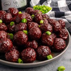 a plate filled with meatballs and green onions next to an instant pressure cooker