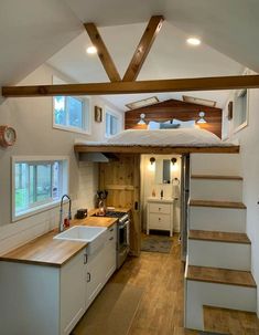 a tiny kitchen and living area in a home with stairs leading up to the loft