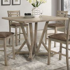 a dining room table with four chairs and a vase full of flowers on the table