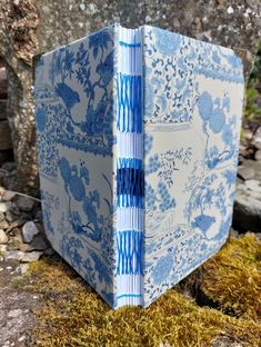 an open blue and white book sitting on top of moss