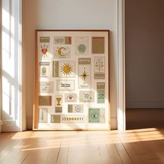 a framed art piece sitting on top of a hard wood floor next to a window