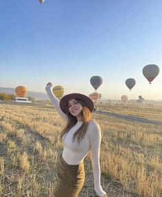 a woman standing in a field with hot air balloons