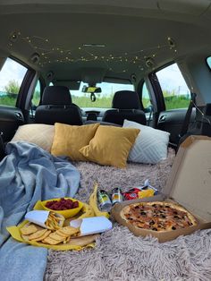 the back of a van with food and drinks in it, including pizza and chips