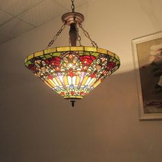 a stained glass light hanging from the ceiling in a room with pictures on the wall