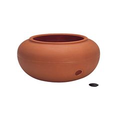 a large clay pot sitting on top of a white floor next to a black object