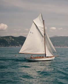 a sailboat with white sails in the ocean