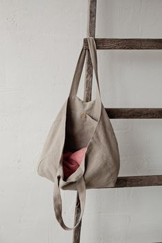 a canvas bag hanging on a wooden ladder with a pink pillow in the bottom pocket