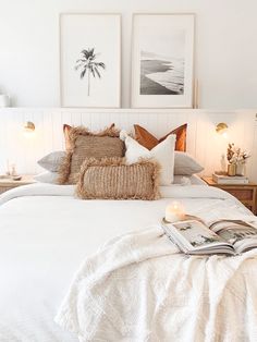 a bed with white sheets and pillows in a bedroom next to two pictures on the wall