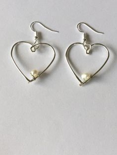 Open silver plated wire heart white fresh water Pearl minimalist dangle earrings. The silver plated wire is tarnish resistant and nickel and lead free. The earring hooks are silver plated and nickel and lead free. This is a perfect gift for a Valentine! Silver Heart-shaped Pearl Earrings For Valentine's Day, Silver Heart Earrings With Pearl Drop As Gift, Silver Heart Earrings With Pearl Drop For Gift, Silver Dangle Heart Earrings With Pearl Drop, Minimalist Sterling Silver Heart Earrings With Ear Wire, Silver Minimalist Heart Dangle Earrings, White Dangle Heart Earrings With Ear Wire, Minimalist Nickel-free Dangle Heart Earrings, Minimalist White Heart Earrings For Everyday