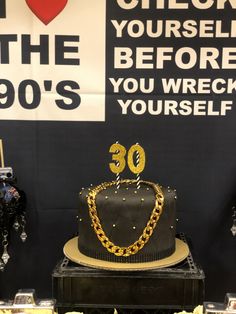 a black cake with gold chains on it sitting in front of a sign that says, i love the 90's