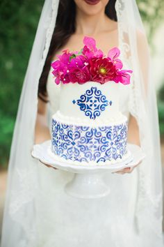 a bride holding a wedding cake with flowers on it