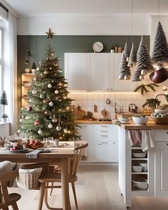 a christmas tree is in the middle of a kitchen with white cabinets and wooden floors