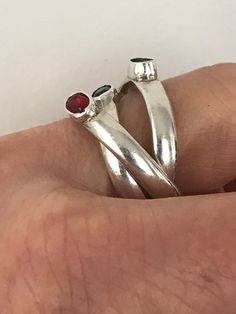 This fun rolling ring is made up of three interlocking sterling silver bands, each bezel set with a green, red or blue glass stones. Each band is marked 925 and is about 3mm wide. This ring is about a size 8 1/2 and is in very good preloved condition. Please see all photos for details, as well as, condition. Thank you for looking! Adjustable Red Sterling Silver Stackable Rings, Red Stackable Open Ring, Red Gemstone Sterling Silver Stackable Rings, Red Gemstone Stackable Rings In Sterling Silver, Silver Three-stone Ruby Ring Gift, Silver Three Stone Ruby Ring As Gift, Red Birthstone Ring With Bezel Setting In Sterling Silver, Filigree Diamond Ring, Rolling Ring