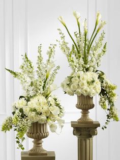 two vases filled with white flowers sitting next to each other