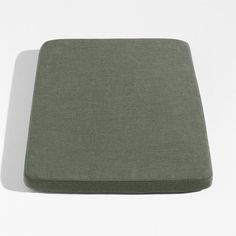 a close up of a green cushion on a white surface with a shadow from the floor