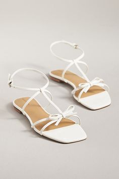 The Reformation Maya Bow Sandals feature a square toe, ankle strap, and delicate bow at the toe for a sweet springtime sandal. | Maya Bow Sandals by Reformation in White, Women's, Size: 6.5, Leather/Rubber at Anthropologie Chic Flat Heel T-strap Sandals For Spring, Chic White Lace-up Sandals With Ankle Tie, Spring Low Heel Shoes With Bow Straps, Spring Low Heel Heels With Bow Straps, Spring Bow Straps Low Heels, Spring Party T-strap Sandals With Low Heel, Summer Lace-up Sandals With Heel Strap And Square Toe, Spring Ankle Strap Sandals With Bow Straps, Summer Sandals With Bow And Adjustable Straps