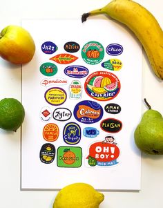 a bunch of stickers sitting on top of a white paper next to some fruit