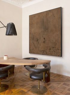 a table and chairs in a room with a painting on the wall