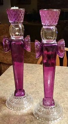 two purple glass candlesticks sitting on top of a table