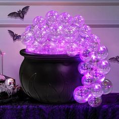 a large pot filled with lots of purple balloons on top of a table next to halloween decorations