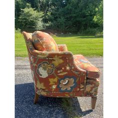 an upholstered chair sitting on gravel in front of trees