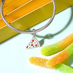 Show off your love for pizza, and food for all occasions with this Delicious Pizza Slice Pendant Dangle Charm. Made in 925 sterling silver, this charm features red enamels and green CZ stones. Wear the Italian-inspired dangle on your bracelet to show the love, or gift it as a treat to someone you know with a love for pizza. Trendy Sterling Silver Charms Jewelry, Trendy Sterling Silver Jewelry With Charms, Trendy Silver Charms For Gifts, Trendy Pendant Charm As Gift, Trendy Pendant Charms As Gift, Trendy Pendant Charms For Gift, Trendy Nickel-free Silver Charms, Metal Heart Dangle Charms, Metal Heart Charm Dangle