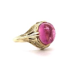 This one of a kind Art Deco ring features a light pink tourmaline in 14 karat yellow gold. The tourmaline reflects a romantic, taffy pink hue. Cabochon cut and smoothly polished. The antique shoulders of the band feature geometric engravings. Decorative and fashionable. Finished in 14 karat yellow gold. This statement cocktail ring is a treasure from the Art Deco era. Classic Pink Ruby Ring For Formal Occasions, Pink Round Cabochon Ruby Ring, Pink Cabochon Ruby Ring, Formal Pink Birthstone Ring With Gemstone, Formal Pink Gemstone Birthstone Ring, Pink Fine Jewelry Birthstone Ring For Formal Occasions, Pink Gemstone Birthstone Ring For Formal Occasions, Pink Birthstone Ring With Gemstone For Formal Occasions, Elegant Pink Ruby Cabochon Ring