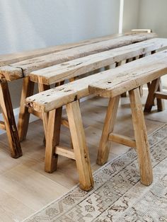 two wooden benches sitting next to each other on top of a carpeted floor in front of a white wall