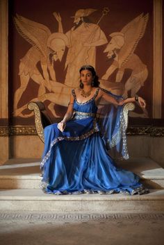 a woman in a blue dress sitting on a chair