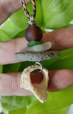 a person is holding some kind of rock and bead on their hand with a shell in the middle