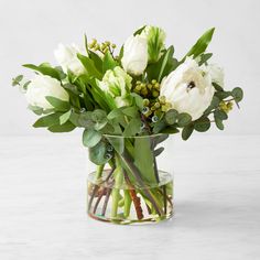 a glass vase filled with white flowers and greenery