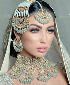 a woman in a bridal gown with jewelry on her head and veil over her shoulder