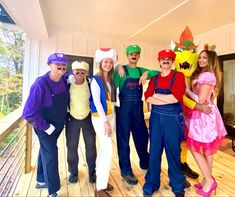 a group of people standing on top of a wooden floor next to each other wearing costumes