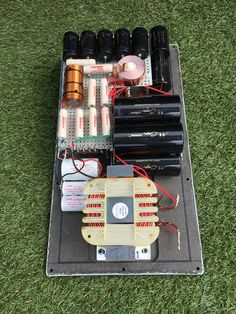 an electronic device is sitting on the ground with many batteries and wires attached to it