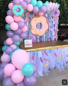 a table topped with balloons and doughnuts next to a sign that says donuts