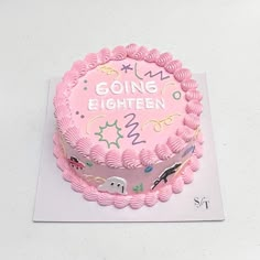 a pink birthday cake sitting on top of a white table next to a sign that says going eighteen