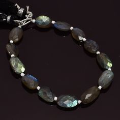 a bracelet with labradorite beads and white bead on a black background, close up