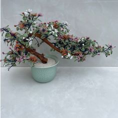 a bonsai tree in a blue bowl with white and pink flowers on it's branches