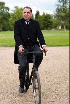 a man in a suit and tie riding a bike