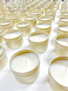 several rows of white candles sitting on top of a table