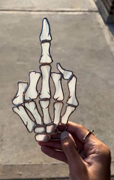 a hand holding up a piece of art made out of stained glass, with white and brown designs on it