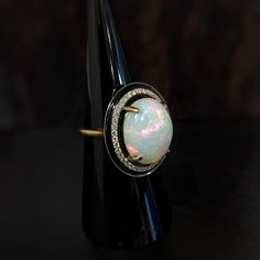 This statement ring features a 7.49 carat oval opal gemstone of size 16x12 mm with a halo of natural earth mined diamonds and black enamel detail, all set in solid 14K gold. This ring can be a beautiful October birthstone gift for your loved ones! This ring is made with solid 14K Gold and natural Earth mined SI / G-H diamonds. As listed, this ring is ready to ship. If you're interested in purchasing this setting with a different center stone please message us! Oval Cabochon Opal Ring In Fine Jewelry, Oval Cabochon Opal Ring Fine Jewelry, Fine Jewelry Oval Cabochon Opal Ring, Modern Round Opal Jewelry, Luxury Polished Opal Ring, Oval Cabochon, Luxury Opal Ring With Oval Cabochon And Polished Finish, Luxury Polished Opal Ring With Oval Cabochon, Oval Opal Rings With Polished Finish, Fine Jewelry Oval Opal Ring With Polished Finish