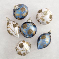 six blue and gold christmas ornaments on a white surface