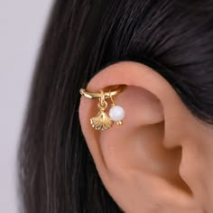 a close up of a person's ear with an earring in the shape of a leaf